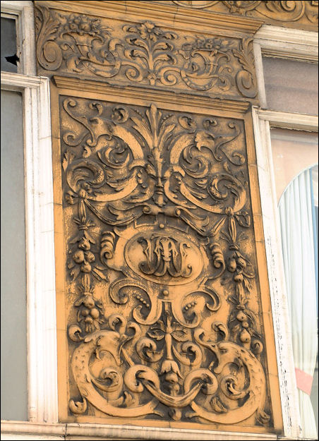 rectangular panel depicting a 'green man' face amid decorative scroll work