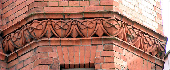 below a corner window bay is a terracotta moulding of a continuous strand of rope which forms a pattern of Stafford Knots in shields