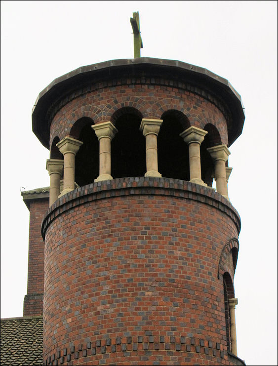 round southwest tower with conical roof over open arcade