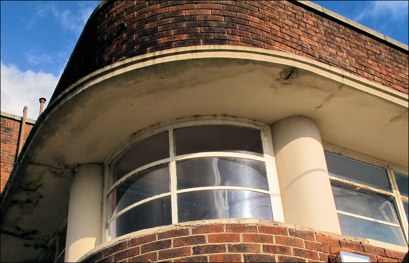 curved and recessed corner steel-framed window with side columns and overhanging canopy