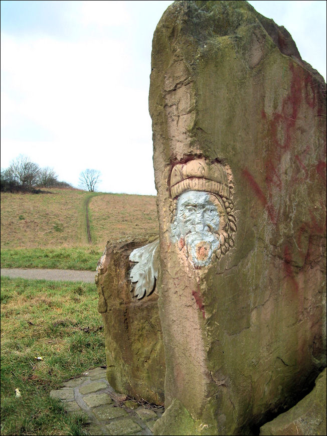 the head of a bearded figure with curly hair wearing what appears to be a bobble hat