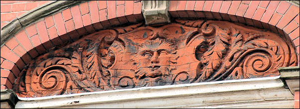 One of three of the panels with a face within a design of foliage and scrolls