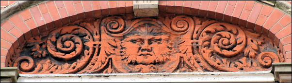 One of three of the panels with a face within a design of foliage and scrolls