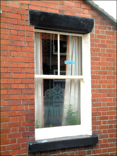 ground floor window with etched glass bearing the name Vaults