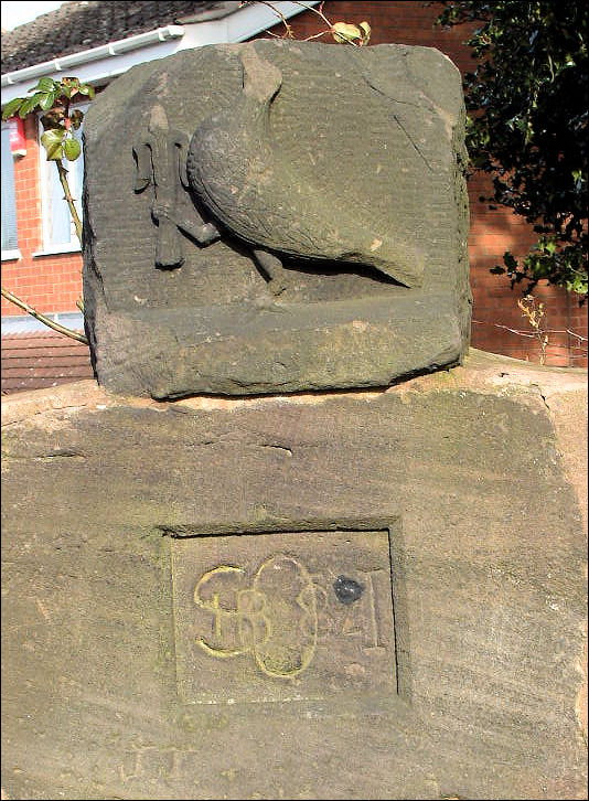 Bird holding a stylised Fleur de Lys  