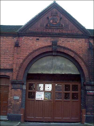 Entrance beneath pedimented gable to the right, with double stepped brick arch and narrower foot-door alongside.