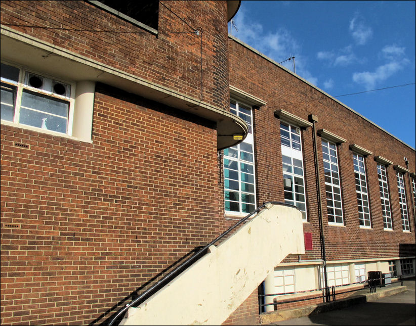 the strong vertical metal casement of the windows to the gym contrast with the detail and columns to the basement windows below 